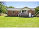 Cozy brick home featuring a well-kept lawn, covered patio, and a classic white trim under a clear blue sky at 1975 Oakridge Duncan Rd, Fuquay Varina, NC 27526
