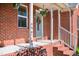 Inviting front porch featuring hanging plants, decorative wreath and red brick steps at 1975 Oakridge Duncan Rd, Fuquay Varina, NC 27526
