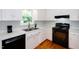 Bright kitchen features white cabinets with gold knobs, stainless steel sink, and a black range at 1975 Oakridge Duncan Rd, Fuquay Varina, NC 27526