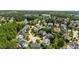 Wide aerial view featuring neighborhood of tree-lined streets, well-maintained homes, and a serene lake in the distance at 307 Beacon Falls Ct, Cary, NC 27519