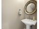 Elegant powder room featuring a pedestal sink, decorative mirror, and neutral wall color at 307 Beacon Falls Ct, Cary, NC 27519