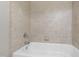A close up of a tiled bathtub and wall, featuring neutral colors and chrome fixtures at 307 Beacon Falls Ct, Cary, NC 27519