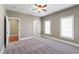 A view of a carpeted bedroom with three doors and two windows with blinds at 307 Beacon Falls Ct, Cary, NC 27519