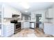 Well-lit kitchen with stainless appliances, white cabinets, and a view to the living space at 4125 Scofield Dr, Raleigh, NC 27610