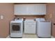 Well-organized laundry room with modern white washer and dryer units, complemented by storage cabinets at 4219 Peachway Dr, Durham, NC 27705