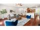 Open living room with hardwood floors, a gray sofa, blue chairs, and view to the kitchen at 4963 Highcroft Dr, Cary, NC 27519