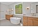 Bright bathroom featuring a soaking tub, herringbone tile flooring, and wood vanities at 503 Damascus Church Rd, Chapel Hill, NC 27516