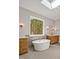 Bright bathroom featuring a soaking tub, wood vanities, and a large window with wooded view at 503 Damascus Church Rd, Chapel Hill, NC 27516