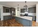 Modern kitchen featuring gray cabinets, quartz countertops, stainless steel appliances, and a large island with pendant lighting at 5545 Silk Hope Gum Springs Rd, Siler City, NC 27344