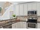 Well-lit kitchen features granite countertops, stainless steel appliances, and tile backsplash at 5940 Dahlberg Dr, Raleigh, NC 27603