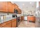 Open kitchen boasts stainless steel appliances, granite counters, and wood cabinets with hardwood floor at 614 Marian Way, Sanford, NC 27330