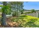 A well-kept lawn with mature trees, a fenced perimeter, and a partial view of a pool at 63 Majestic Oak Dr, Garner, NC 27529