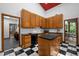 Kitchen with black and white floor tile, wood cabinets, and black appliances at 6700 Falconbridge Rd, Chapel Hill, NC 27517