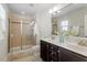 Well-lit bathroom with double vanity, glass-enclosed shower, and neutral tiles at 7879 Allscott Way, Raleigh, NC 27612