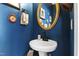 Stylish half-bathroom with blue walls, pedestal sink, round mirror, and elegant decor at 818 Bryant St, Raleigh, NC 27603