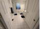 Well-lit bathroom features a shower with glass doors, white tile floor, and white cabinets at 908 E Hudson Ave, Durham, NC 27704