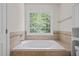Bright bathroom featuring a large soaking tub with tiled surround and a window overlooking the trees at 9508 Waterwood Ct, Raleigh, NC 27614