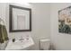 Cozy half bathroom featuring a pedestal sink, framed mirror, floral art, and neutral paint at 9508 Waterwood Ct, Raleigh, NC 27614
