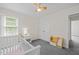 Bright bedroom with gray carpet, two windows, a crib, and a bookshelf at 9508 Waterwood Ct, Raleigh, NC 27614