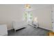 Bedroom room with gray carpet, two bright windows, white crib, and a cute bedside table at 9508 Waterwood Ct, Raleigh, NC 27614