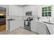 Well-lit kitchen featuring white cabinetry, stainless appliances, and tile flooring at 9508 Waterwood Ct, Raleigh, NC 27614
