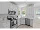 Bright kitchen featuring white cabinets, stainless steel appliances, and a subway tile backsplash at 9508 Waterwood Ct, Raleigh, NC 27614