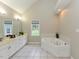 Bright bathroom featuring a double sink vanity, tile flooring, and a luxurious soaking tub under a window at 1005 Fairfax Woods Dr, Apex, NC 27502