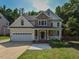 Charming two-story home featuring a stone facade, attached garage and manicured front lawn at 1005 Fairfax Woods Dr, Apex, NC 27502