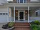 Close-up of front porch with classic black door, brick steps and manicured garden beds at 1005 Fairfax Woods Dr, Apex, NC 27502