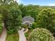 Aerial view of a gray home nestled among lush trees, featuring a circular driveway and well-manicured lawns at 105 Jolyn Pl, Chapel Hill, NC 27517