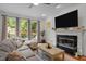 Cozy living room featuring a fireplace, large TV, and comfortable seating with natural light from the windows at 105 Jolyn Pl, Chapel Hill, NC 27517