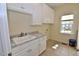 Bright laundry room with white cabinets, marble countertop and sink beneath window at 1126 Falling River Walk, Rocky Mount, NC 27804