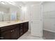 Bathroom featuring double sink vanity with dark cabinets, large mirror, and a walk-in closet at 115 Snowy Orchid Ln, Smithfield, NC 27577
