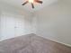 Bedroom with a ceiling fan, carpet, window, and closet doors creating a cozy and functional space at 115 Snowy Orchid Ln, Smithfield, NC 27577