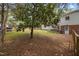 Backyard featuring mature trees, a wooden fence, and a glimpse of the home's exterior with a well-kept lawn at 1205 Willow Dr, Chapel Hill, NC 27517