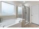 Bathroom featuring a soaking tub next to a glass enclosed shower and frosted window at 1320 Cozy Oak Ave, Cary, NC 27519