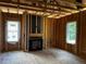 An unfinished living room featuring natural light, a fireplace, and exposed wood framing at 146 Seahawk Way, Zebulon, NC 27597