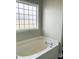 Bathroom with a tiled bathtub surround with a large window that provides plenty of natural light at 1618 Brownairs Ln, Raleigh, NC 27610