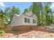 Rear exterior view of a home featuring white siding, a brick foundation, and lush, mature trees at 1952 Lewis Dr, Burlington, NC 27215