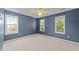 This empty blue bedroom with carpet features three windows and a ceiling fan at 2037 Summer Shire Way, Raleigh, NC 27604