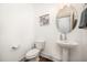 A modern half bathroom features a pedestal sink, toilet and decorative wall art at 283 Daniel Ridge Rd, Wendell, NC 27591