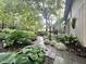 Landscaped backyard featuring a stone walkway, mature trees, and flower beds at 2900 Sylvania Dr, Raleigh, NC 27607
