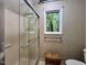 Bathroom showcasing glass-enclosed shower, natural light from window, complemented by a wooden bench and toilet at 2900 Sylvania Dr, Raleigh, NC 27607