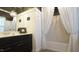 Elegant bathroom featuring dual sinks, beaded chandelier, large mirror and tub with decorative curtains at 308 Wescott Ridge Dr, Holly Springs, NC 27540