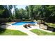 A serene pool area with sun loungers and a bar, surrounded by a lush, fenced backyard at 308 Wescott Ridge Dr, Holly Springs, NC 27540