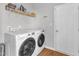 The laundry room offers a side-by-side washer and dryer, a shelf, and a white door at 3119 Guiding Light Rd, Raleigh, NC 27610