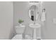Stylish powder room with a pedestal sink, toilet, and decorative mirror at 3119 Guiding Light Rd, Raleigh, NC 27610