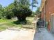 A partially overgrown backyard features a brick house and several play structures at 3323 Baugh St, Raleigh, NC 27604