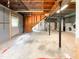 Unfinished basement featuring concrete walls and flooring, with exposed beam ceiling and access to stairs at 3323 Baugh St, Raleigh, NC 27604