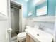 Well-lit bathroom featuring blue and white tile, shower with curtain, toilet, and modern sink at 3323 Baugh St, Raleigh, NC 27604